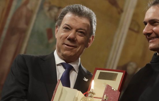 Colombian President Juan Manuel Santos receives the St. Francis lamp peace prize  by  Father Mauro Gambetti during a ceremony in Assisi's Basilica, Italy, Saturday Dec. 17, 2016. Pope Francis is doing his part to unite Colombians divided by a peace deal with leftist rebels by sponsoring a surprise meeting on Friday between President Juan Manuel Santos and his harshest critic. (AP Photo/Gregorio Borgia) |
